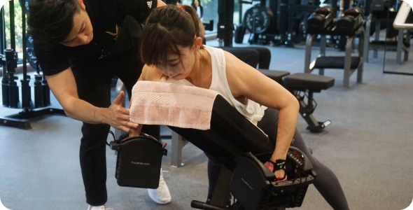 Two people exercising with fitness coach in gym.