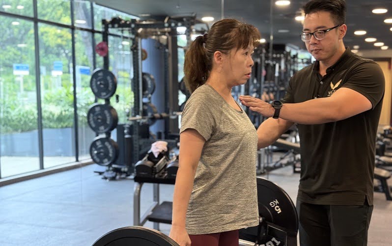 Personal trainer guiding woman during strength exercise for menopause health.