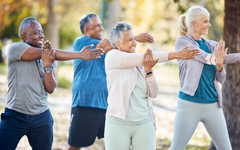 A diverse group of active seniors practicing outdoor stretches.