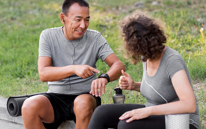 Senior man tracking fitness data on smartwatch after outdoor exercise.