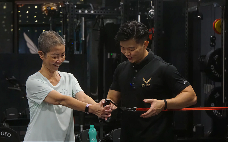 Vigeo trainer guiding an older adult during strength training.