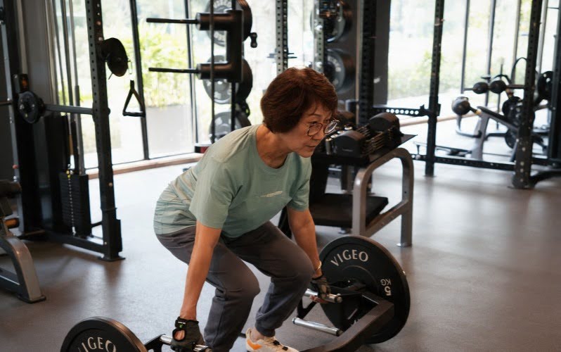 Senior woman lifting barbell to improve bone density and strength
